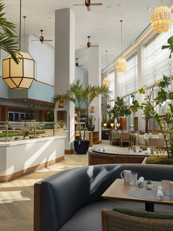 A spacious, modern restaurant features a buffet counter and set tables amidst abundant indoor plants, high ceilings, and large windows with blinds.