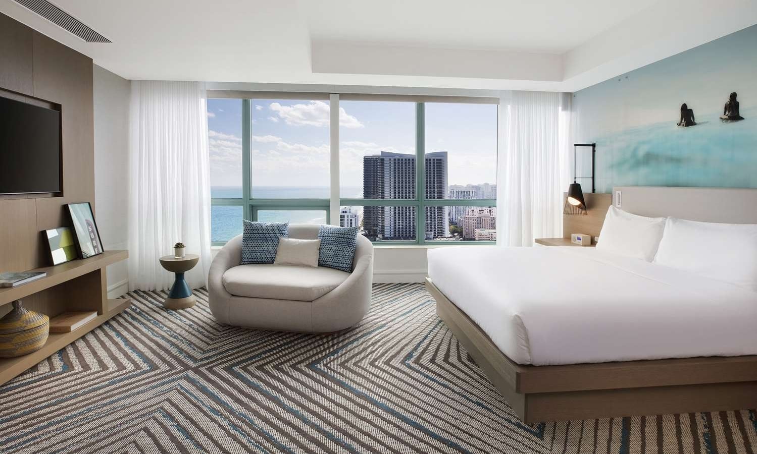 Presidential Suite bedroom featuring a king bed, large oval lounge chair, mounted TV, and modern decor