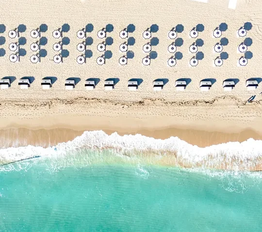 An aerial, top-down view of the Diplomat Beach shoreline with rows of lounge chairs